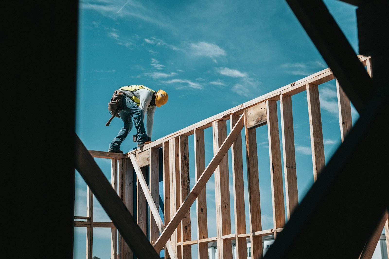 Construction worker in a hard hat on a steel building frame – Bobby's HOME-P2 thematic spec for Builders ('project site'). Finalised stand-in (Unsplash, Josh Olalde; see public/assets/platform/LICENSES.md).