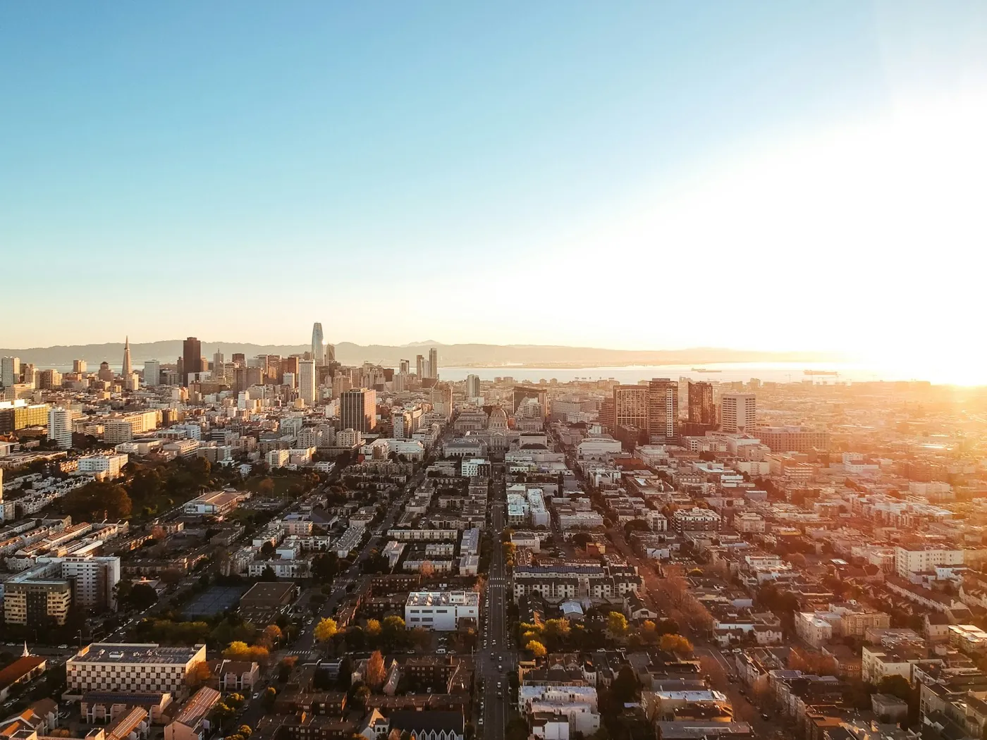Aerial view of a city neighbourhood at golden hour, residential blocks reaching toward a distant skyline – the long-term, lived-in value the platform is built to create. Stand-in (Unsplash, Robert Bye; see public/assets/platform/LICENSES.md).