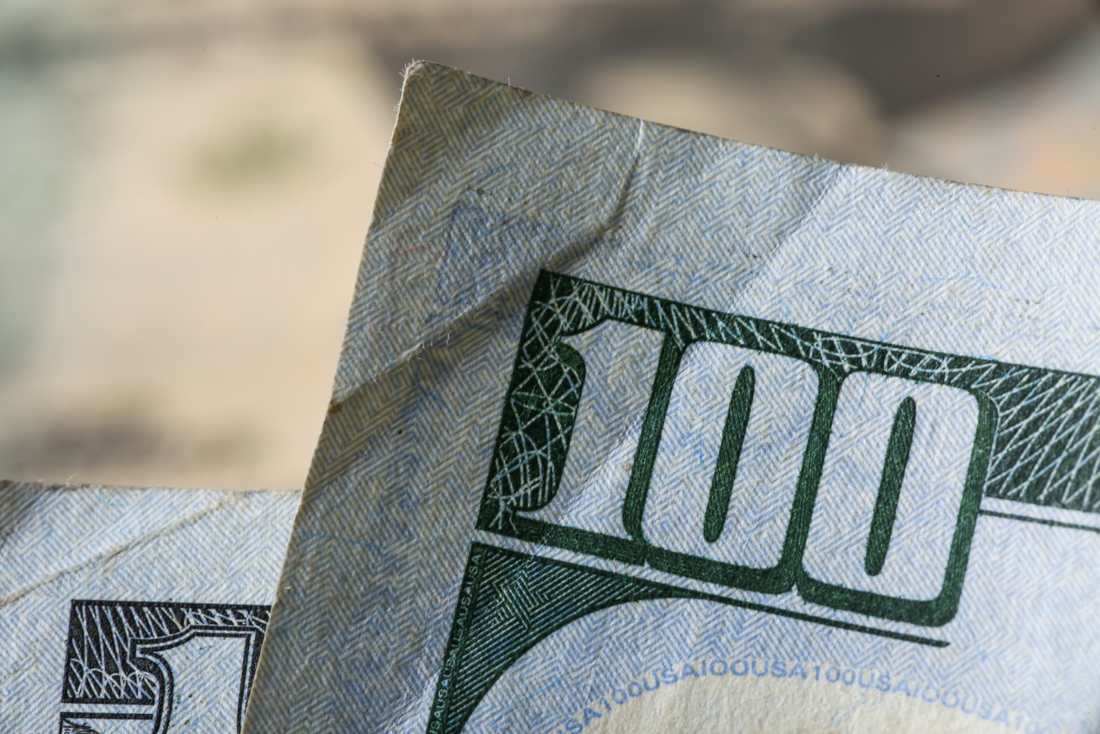 Macro close-up of a US one hundred dollar bill – Bobby's HOME-P2 thematic spec for Capital ('reference to money'). Stand-in (Unsplash, Giorgio Trovato; see public/assets/platform/LICENSES.md).